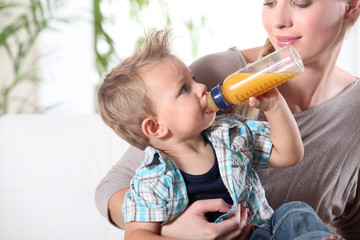 Child drinking juice in his mother's lap