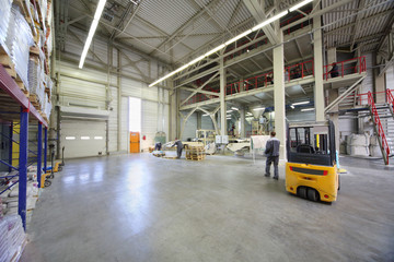 Men in gray uniform work in large warehouse