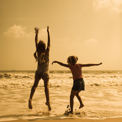 Two happy kids jumping on the beach