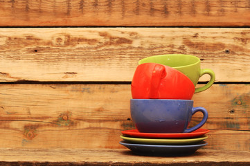 Colorful cups on the wooden background