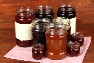 Tasty jam in banks on wooden background
