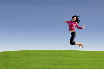 Happy entreprenur jumping over green field