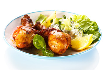 Grilled chicken legs and vegetables on white background