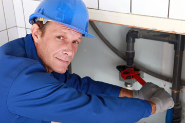 Plumber using a wrench on a water pipe