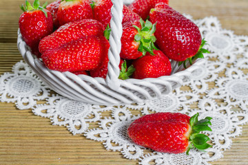 Ripe strawberries in ceramic basket on wooden background