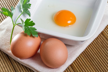 Broken egg in a bowl with parsley