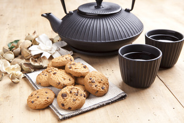 beautiful teapot with chocolate biscuits on wooden table, delici