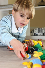 Little blond boy playing with toys