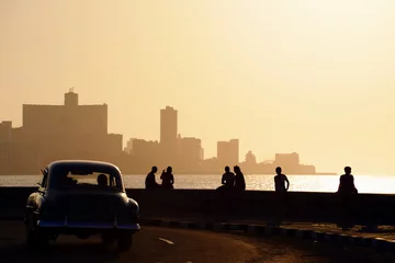 Fotobehang Oldtimers Mensen en skyline van La Habana, Cuba, bij zonsondergang