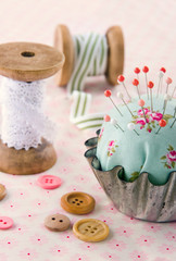 Handmade pincushion on floral fabric background