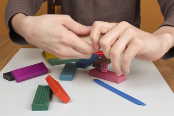Boy moulds from plasticine on table