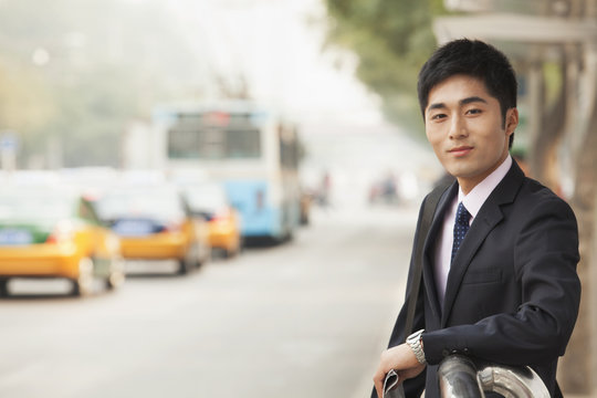 Young businessman waiting at the bus stop for the bus