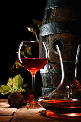 A glass of red wine next to a decanter