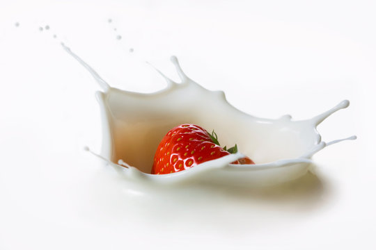 Red strawberry fruits falling into the milk