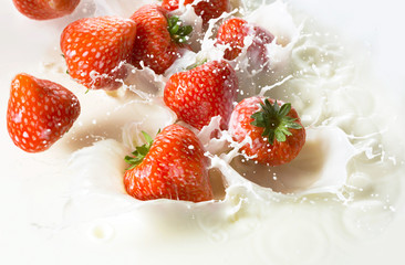 Red strawberry fruits falling into the milk
