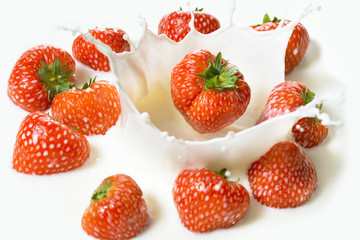 Red strawberry fruits falling into the milk