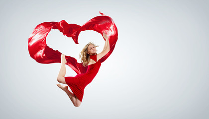 Fototapeta na wymiar Dancing young woman with flying fabric