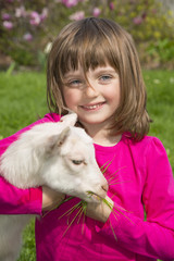 little girl with little goat in the spring garden