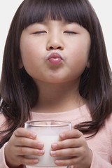 Portrait of girl drinking a glass of milk, making a face