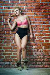 girl in swimsuit posing provocatively in front of a brick wall