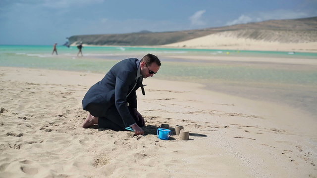 Businessman building sandcastle on beautiful beach