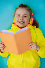 Young girl in headphones reading a book