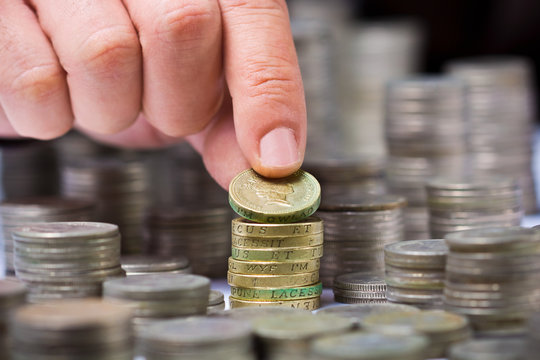 Closeup of stack of british pound coins with a male hand