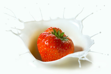 Red strawberry fruit falling into the milk