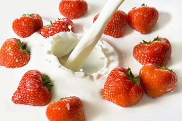 Red strawberry fruits falling into the milk
