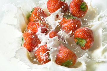 Red strawberry fruits falling into the milk