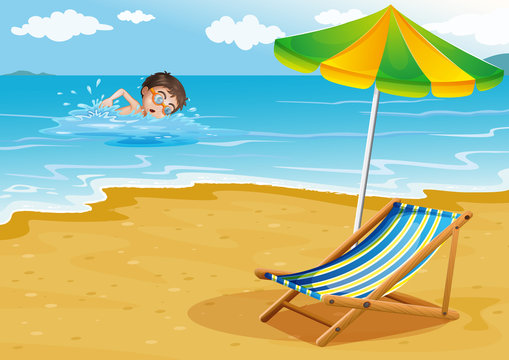 A boy swimming at the beach with an umbrella and a bed