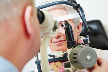 Senior woman behind slit lamp at optician