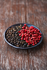 Black and pink peppercorns on a small plate