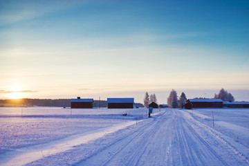 Snow covered road at winter evening with sunset