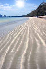 Wave patterns blow sand on the beach.