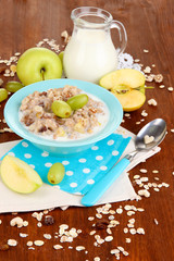 Useful oatmeal in bowl with fruit on wooden table close-up