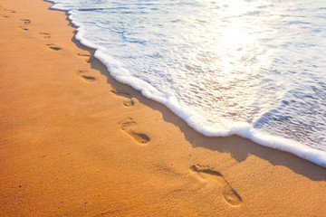 beach, wave and footsteps at sunset time