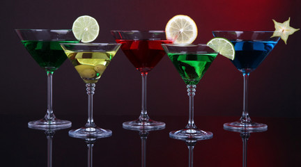 Alcoholic cocktails in martini glasses on dark red background