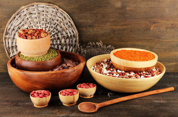 Different kinds of beans in bowls on wooden background
