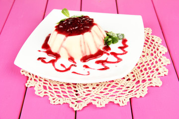 Panna Cotta with raspberry sauce, on color wooden background