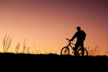 silhouette of a cyclist with sunset background