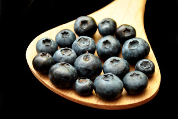 Wooden Spoon with Blueberries Over Black