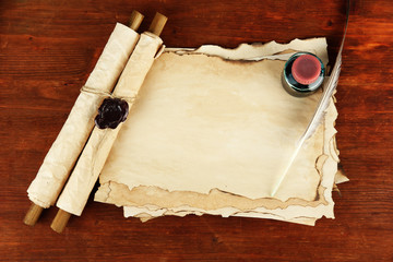 Old paper, ink, scrolls and feather on wooden background