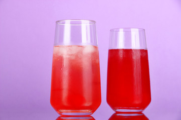 Two cherry cocktails with ice on purple background