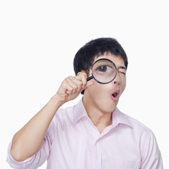 Young man looking through magnifying glass