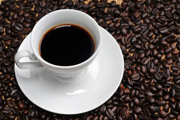 Obraz premium Cup of coffee on coffee beans background