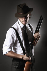 Handsome gangster posing with shotgun and hat