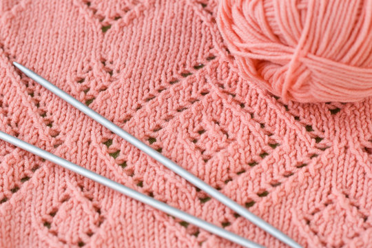 A fragment of a knitted blankets, pink skein of yarn