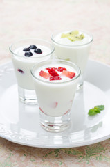 three yogurt with fruit in a glass beaker vertical