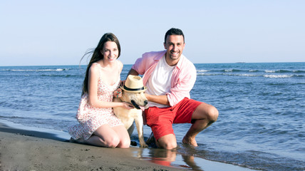 Happy family playing with dog on beach